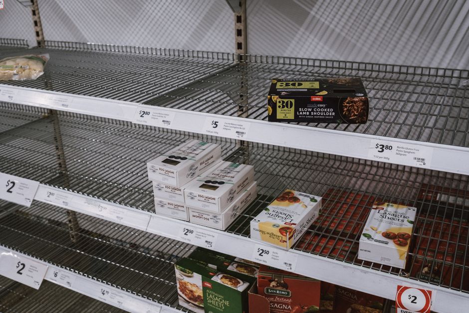 A minimal shot of long, empty wooden shelves in a hardware or building supply store, visually conveying the concept of material shortages and supply chain issues.